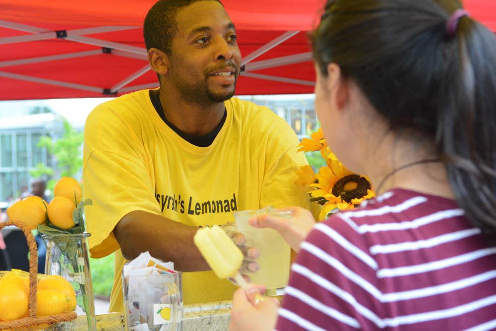 Dominique Edgerton hands a student a cold glass of lemonade at the lemonade stand at Wolf Plaza on April 28. Edgerton served lemonade with Fahsyrah's Lemonade, a local business, one of many that accepted LDOC, or last day of classes, vouchers from students for free food.