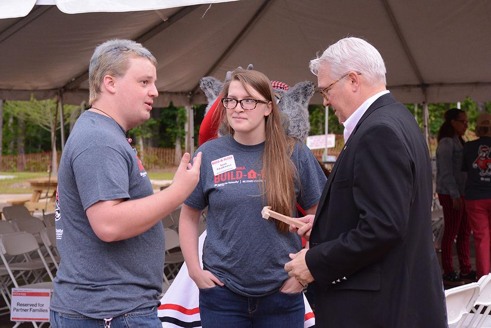 Tripp Pearce, a senior studying environmental engineering and president of NCSU's Habitat for Humanity Chapter for the 2016-2017 year, Sarah Paluskiewicz, a graduate student studying textile engineering and Build-a-Block co-chair, and Chancellor Randy Woodson talk before the Build-a-Block dedication ceremony. Pearce and Paluskiewicz presented Woodson with a wooden hammer before the ceremony in which eleven townhomes were dedicated to the partner families at the Lake Wheeler Build-a-Block site on Saturday, May 6, 2017.