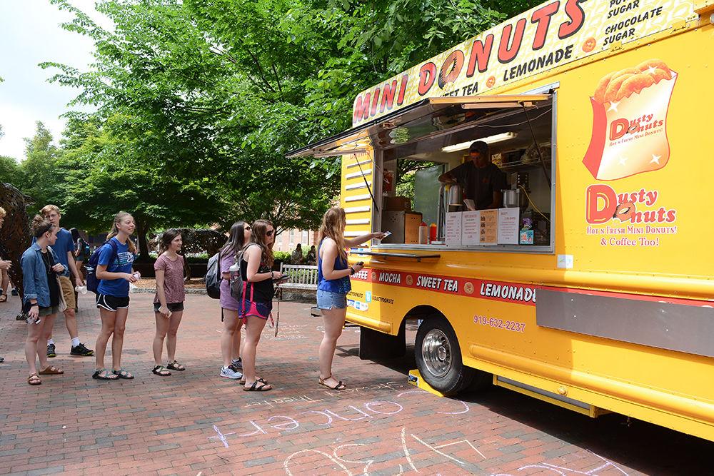 A student gives her voucher at the front of a line to receive free donuts from the Dusty Donuts food truck at Wolf Plaza on April 28. Dusty Donuts was among one of several food truck vendors to come out to serve students as part of the LDOC, or last day of classes, festivities hosted by the Union Activities Board.