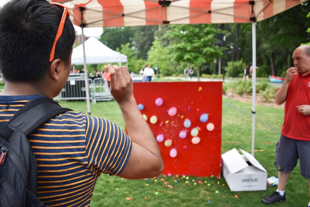 Emanuel Cruz, a junior studying nuclear engineering, aims to throw a dart to pop one of the balloons on the board in Stafford Commons on the last day of class, April 28. Students who successfully popped three balloons in a row were rewarded with a prize such as sunglasses or water bottles.