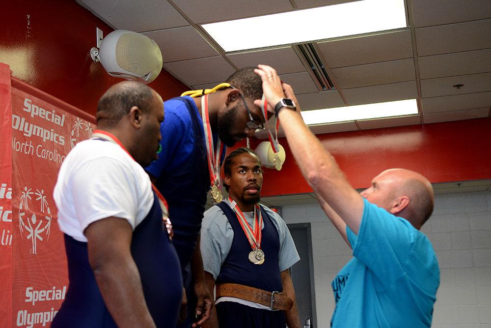 Volunteer Jon Persson presents a gold medal award to Daquan Locke from New Hanover County for his division in the triple combo competition of the powerlifting event while bronze medal winner Charles Quick from Durham County and silver medal winner Brian Carter look on as part of the Summer Special Olympics Saturday, Jun 3 2017. Powerlifting was among several events taking place on campus during the Special Olympics Summer Games. The Olympics allow those with disabilities across North Carolina the chance to compete in various sporting events.