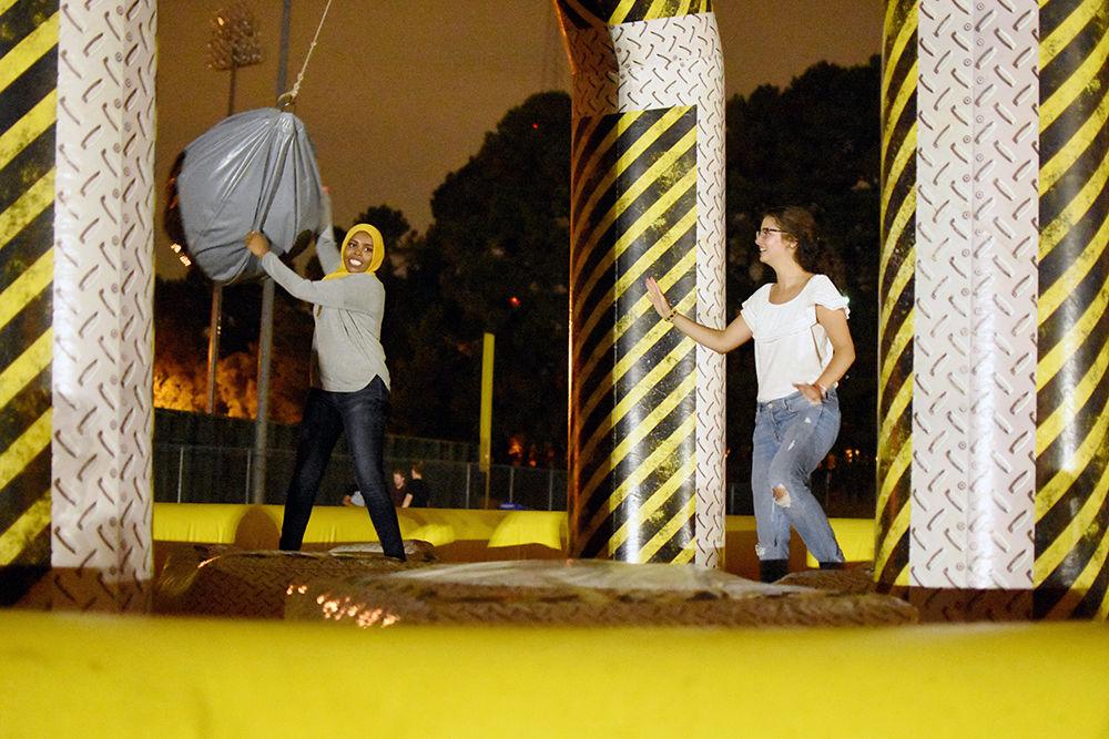 Aisha Merkt a fourth-year Meredith student studying food science and nutrition and Eiman Ali a Meredith alumuns try to knock each other off a pedestal in the wrecking ball inflatable at Wolfpack After Dark. The Union Activity Board hosted the event on Friday, Aug. 25 on Lee Field. They offered a variety of food and activities including a dance party, multiple inflatable games and free pizza.
