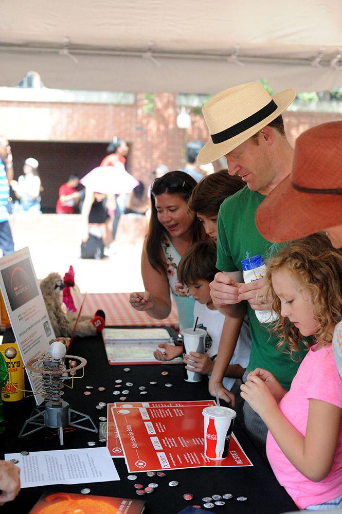 A family gathers around an information table outside of D.H. Hill library on Monday, Aug. 21. There were many information booths around the area to educate individuals and families on what was going on. These booths also handed out free goodies that reminded people of this significant occurrence.