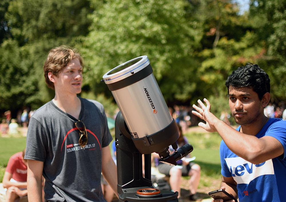 Matthew Gilmer a graduate student studying astrophysics instructs Md Hafizul Islam a fourth-year PhD student studying engineering on using a telescope in the Brickyard to view the solar eclipse on Monday, Aug. 21. "I was appointed to this by my advisor," Gilmer said. The telescope was loaned from the College of Sciences, according to Gilmer.