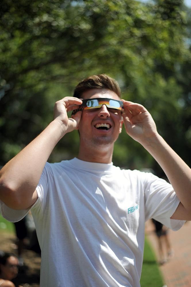 Nolan Joyce a second-year studying Engineering looks at the sun next to the wolf ears on Monday, Aug. 21. Thousands of students gathered around the NC State brickyard to enjoy eclipse festivities. Eclipse glasses were handed out to students and families attending the event.