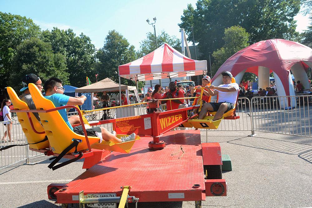Loi Pham, a second-year studying computer science and Johnny Lin, a second-year studying computer engineering, push a lever on one side while Jimmy Zhang, a second-year studying computer science and Dominic Rivero, a second-year studying mechanical engineering, push a lever on the other end on the "Wizzer" ride at the Play Zone during Packapalooza Saturday. The Play Zone at Packapalooza offered students a chance to enjoy themselves on different rides and activities including bungee jumping and inflatable water slides in addition to the &#8220;Wizzer.&#8221;