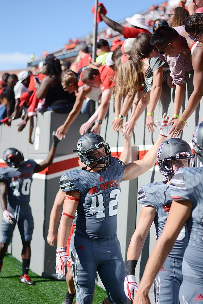 Redshirt-freshman Dylan Autenrieth high fives fans as he exits the field. The NC State football team beat Syracuse 33-25 at Carter-Finley Stadium on Saturday.