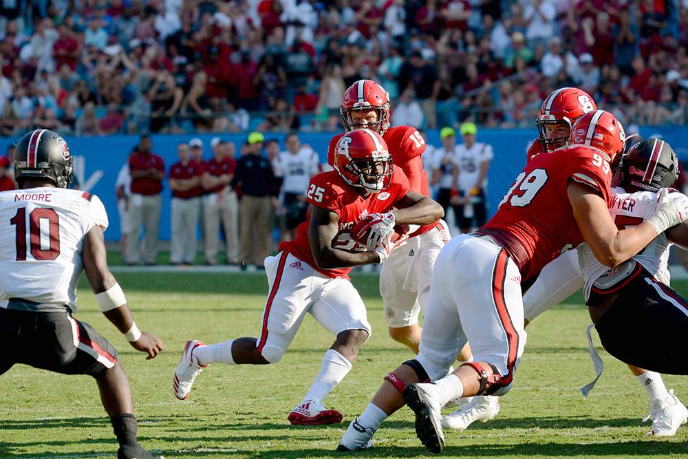 Junior running back Reggie Gallaspy II recieves the handoff from redshirt junior quarterback Ryan Finley against the Gamecocks. The Wolfpack lost the game against South Carolina 35-28. The game was played in Bank of America Stadium on Saturday, Sept. 2.