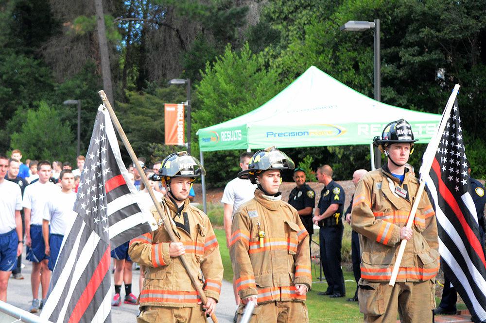 Firefighters Ben Armstrong (right) and Colton Cockman (left) carry U.S. flags to lead the beginning of the second annual 9/11 Memorial Run Sunday morning in Stafford Commons. The modified U.S. flag shown is black and white with one red stripe down the middle, a symbolic representation of the "thin red line," which is often used to show respect for firefighters injured and killed in the line of duty.