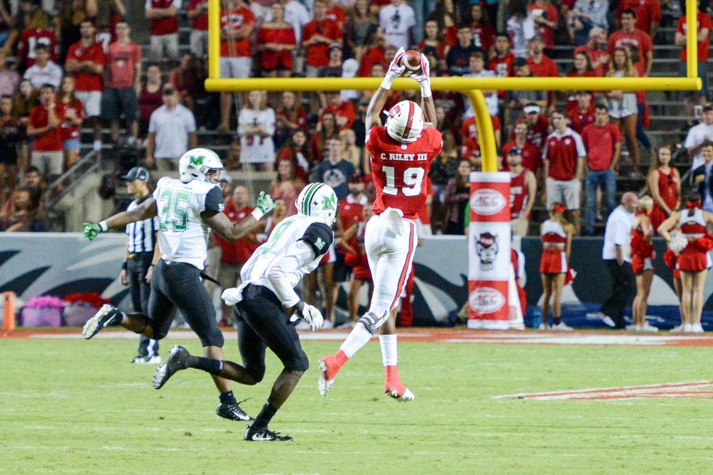 C.J. Riley, a redshirt freshman wide reciever, catches a high pass from QB, Ryan Finley, under Marshall' pressure. The game took place in Carter-Finley Stadium on Sat Sept 9, 2017 at 6pm.