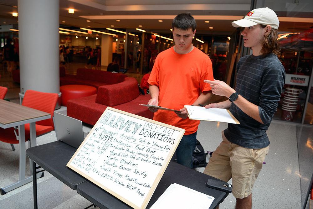 Brendan Vasarhelyi, a second-year studying environmental engineering, explains to Ricardo Mazariegos, a second-year studying business administration, how to get people to donate to relief efforts for Hurricane Harvey at Talley Student Union Wednesday. Vasarhelyi is an off-campus intern with the nonprofit organization North Carolina Public Interest Research Group, or NCPIRG, which held a fundraiser in Talley Student Union to support the victims of Hurricane Harvey.