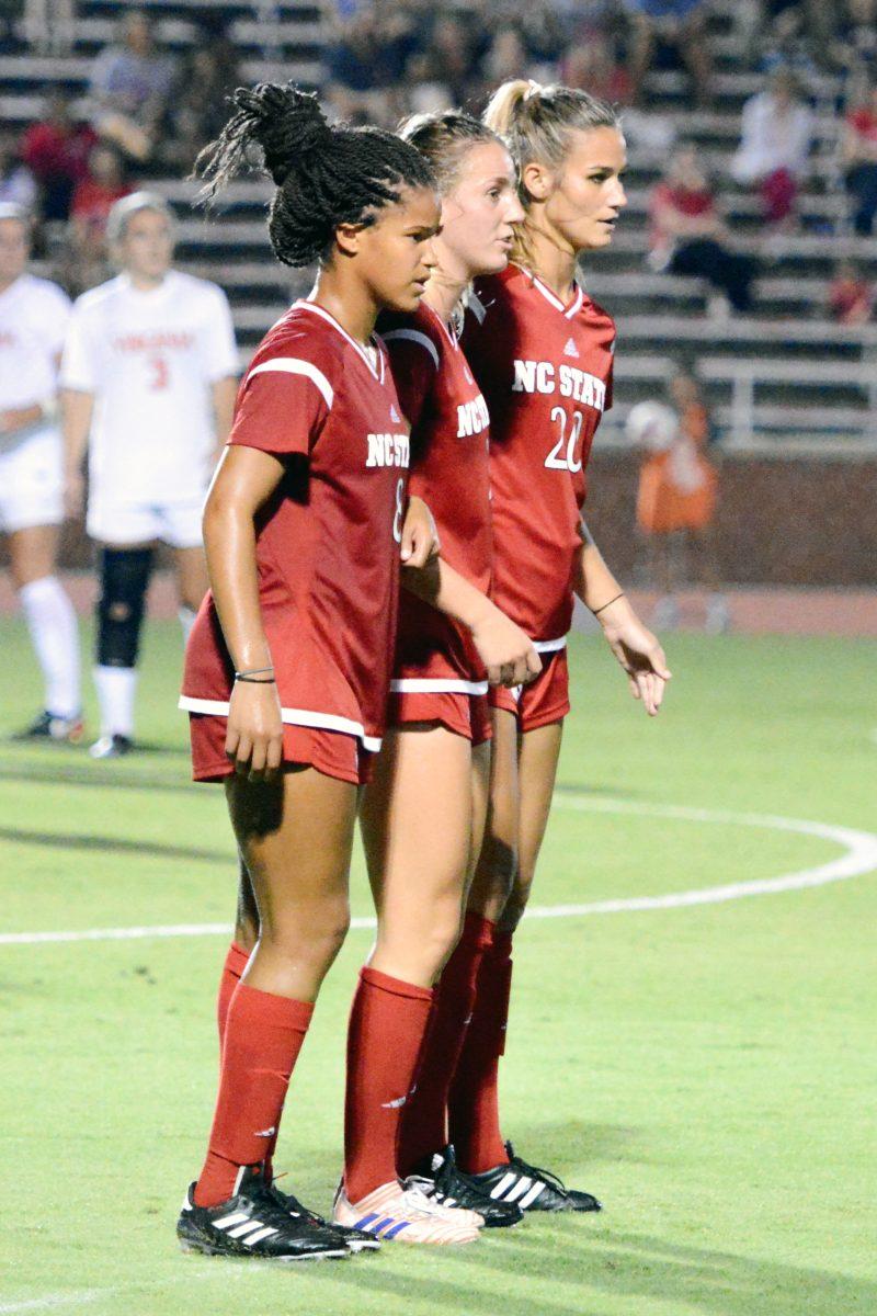 Sophomore midfielder Kia Rankin, sophomore defender Krissi Schuster and redshirt-senior forward Rachel Cox line up to attempt to stop a free kick. The NC State women's soccer team tied Virginia 0-0 in double overtime at Dail Soccer Stadium on Friday, Sep. 15.