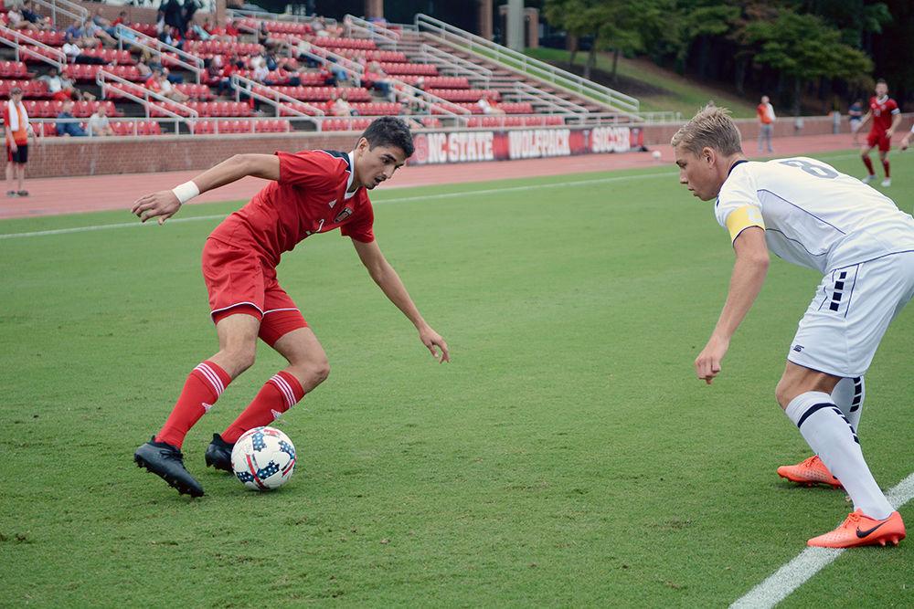 Freshman forward Manny Perez runs while dribbling the ball around an LIU Brooklyn player. The NC State men's soccer team was winning 1-0 Friday against LIU Brooklyn at Dail Soccer Stadium before suspension due to inclement weather.&#160;