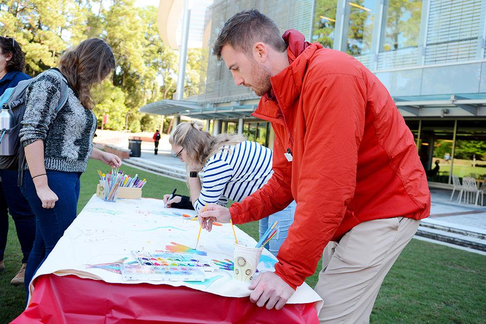 Pharmacy Intern Mark Tiffany paints a colored hand on a poster during the Southern Smash event at Stafford Commons Tuesday. According to McCall Dempsey, founder of Southern Smash, the event started 5 years ago and is held at different universities across the country to promote positive body image and awareness of eating disorders.