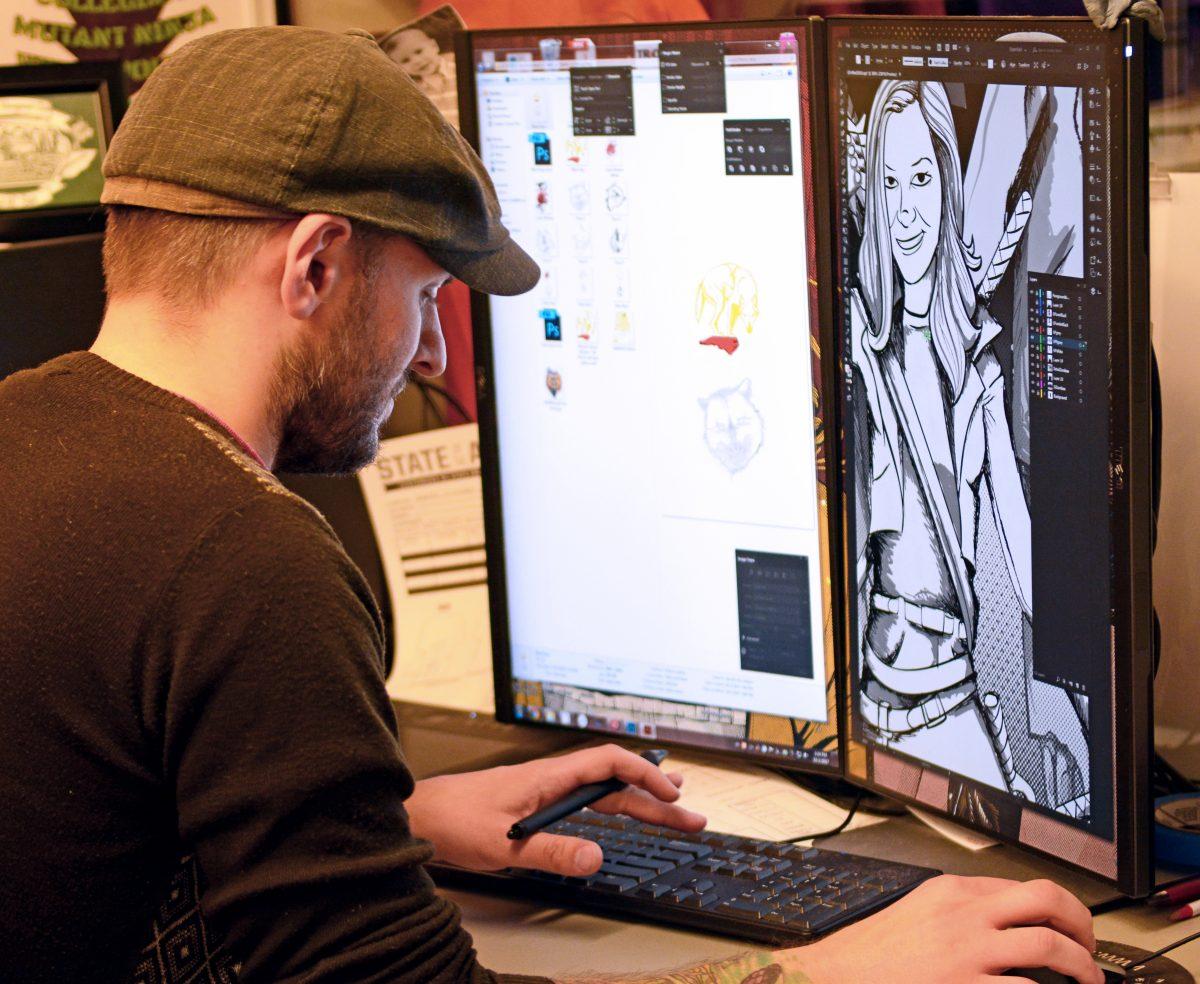 Rich Lombardi, founder and manager of State of the Art, works on a commissioned design of a woman fighting zombies at his workstation in State of the Art in Talley Student Union on Monday, Oct. 2. According to Lombardi, the commissioned design is a birthday present. Commissioned designs can be pressed on t-shirts, made into print outs or sent to Wolf Express and turned into posters.
