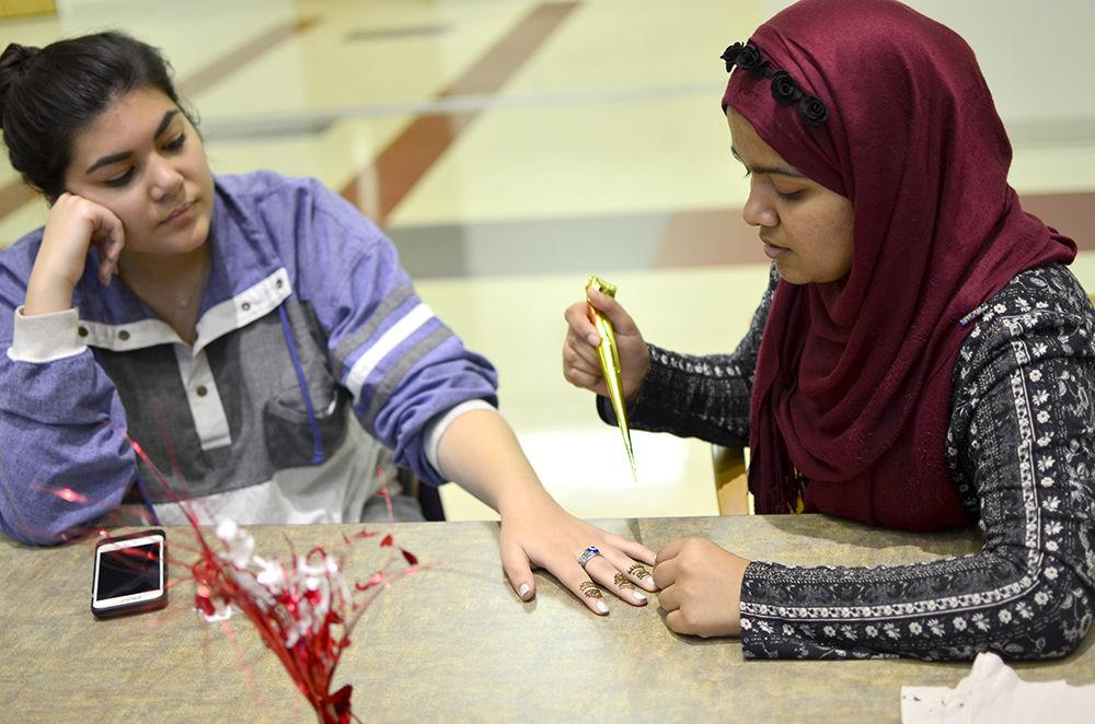 Vice President of the Muslim Student Association, Sinthia Shabnam, gives classmate Zerwa Syed a henna tattoo at the Islam Fair on Tuesday. Sinthia is a third-year at studying political science and sociology and Zerwa is a first-year studying international studies.