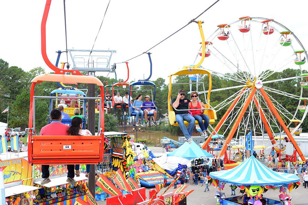 Fairgoers ride on the State Fair Flyer next to a Ferris wheel at the North Carolina State Fairgrounds Friday. The flyer was introduced last year and allows fairgoers the opportunity to view the fair from above. This year marks the 150th Annual State Fair.