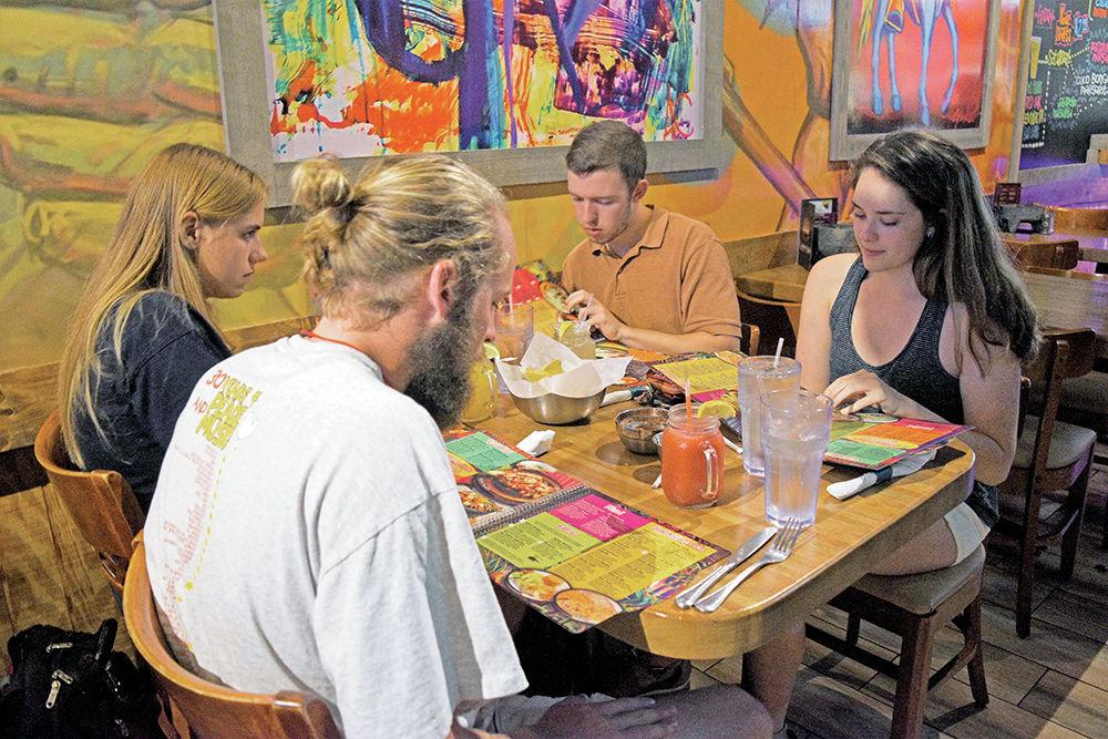 Emily Sikkel, a third-year studying art and design, Jackson Hudson, a fourth-year studying industrial engineering, Jacob Jerrett, fourth-year studying civil engineering, and Miranda Mozick, fourth-year studying civil engineering, look through their menus before deciding what to eat at Coco Bongo Monday. Sikkel and Jerret tried the restaurant for the first time.