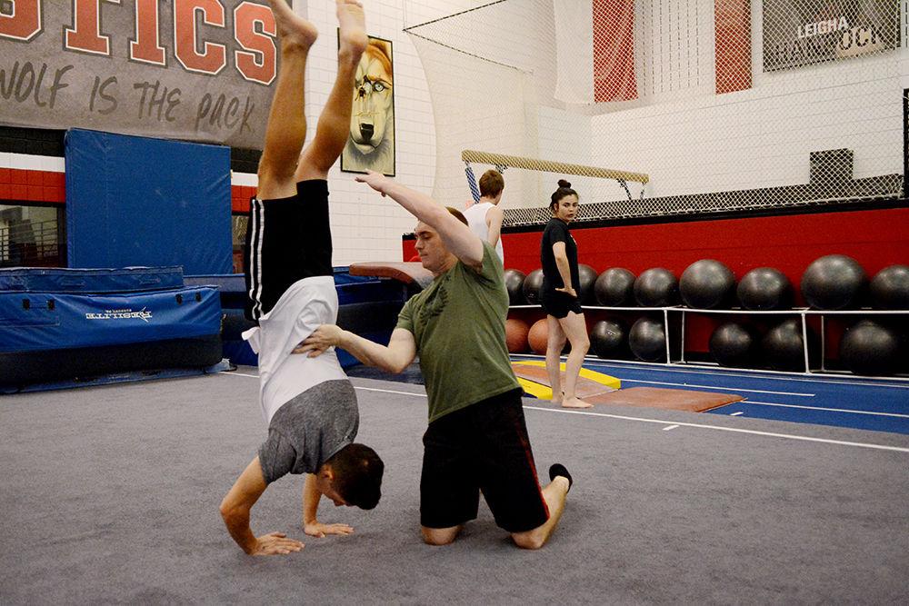 The president of the Gymnastics Club, Brandon Simpson, a fourth-year studying biology, helps Tyler Karpowich, a first-year studying biomedical engineering, with his back handspring. The Gymnastics Club meets every week on Sunday in Carmichael Gym.