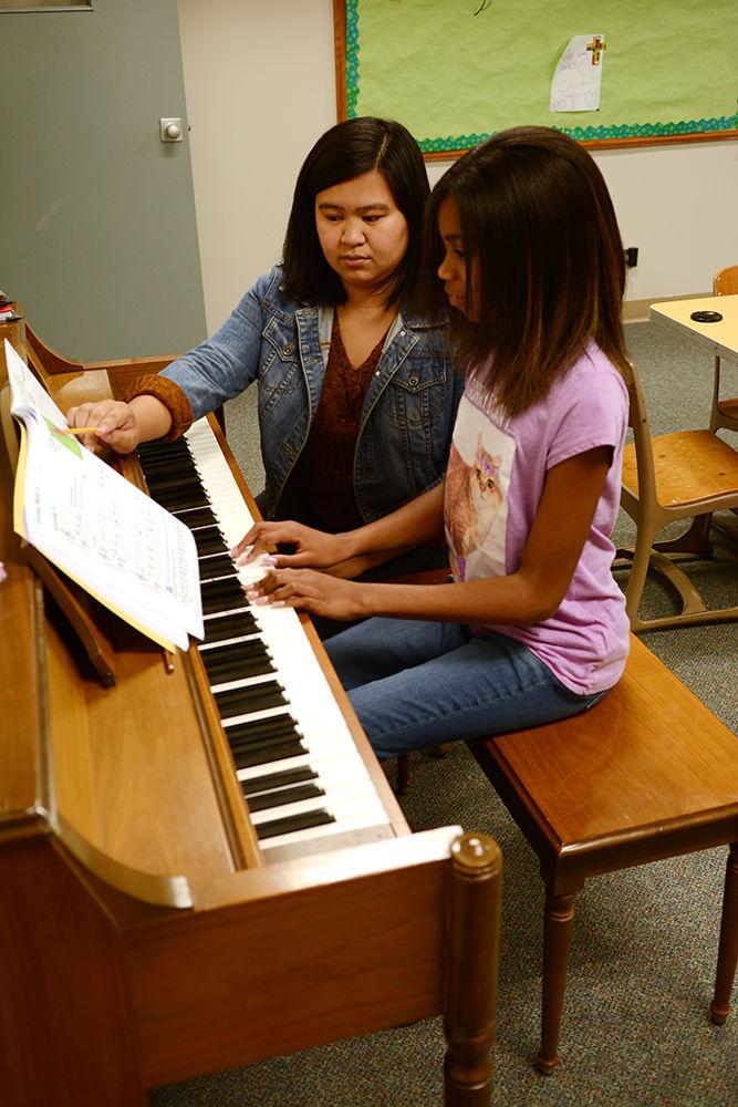 Gabbie Consing, a second year studying psychology walks Ke'mora Poore through a new piece of music on Tuesday at Holy Trinity Lutheran Church. Gabbie is a part of Musical Empowerment, a group that seeks to serve Raleigh youth who may not have access to music lessons without their help. The program provides free instruments, books, and trainings to the participants.