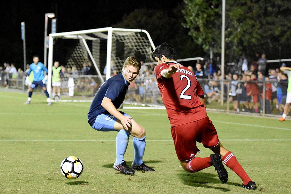 Freshman forward Manny Perez fights to get past a defender from UNC-Chapel Hill in the men's soccer match hosted in WakeMed Soccer Park on Friday. The Wolfpack fell to the Tar Heels in a 0-1 loss.