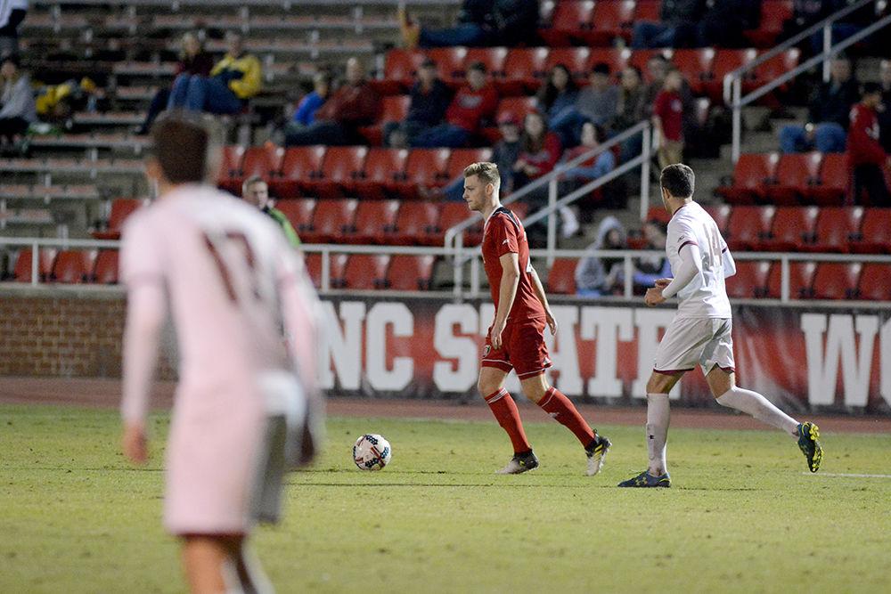 Senior midfielder Jan-Luca Ahillen looks for a teammate to pass the ball to while being pursued by a defender during the NC State vs. Boston College men's soccer game at Dail Soccer Stadium on Friday, Oct. 27. The Wolfpack drew with the Golden Eagles after overtime with a score of 0-0.