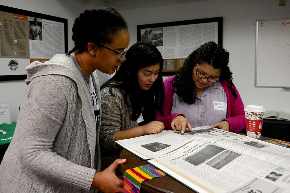 Alysia Dauntain, a first-year studying animal science, Sam Chan, a second-year studying political science and Student Body President Jackie Gonzalez look at archives of the Nubian Message at the 25th anniversary celebration of the publication at the African American Cultural Center Thursday, Nov. 30.