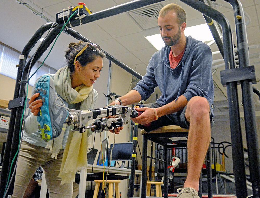 Andrea Brandt, a Ph.D. student studying biomedical engineering, helps Charles Humphries, a third-year studying mechanical engineering, remove a motor-powered lower leg prosthetic in a lab in Engineering Building III on Nov. 21. With her research, Brandt aims to improve upon the performance of lower limb prosthesis in everyday life. "There isn't as much research for prosthetic legs as there is for prosthetic arms" Humphries said when asked about his decision to participate in the research.