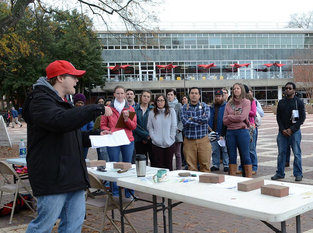 Mike Madden, a third-year PhD student studying atmospheric science, speaks in the Brickyard to a crowd of protesters against the recent tax reform bill passed by Congress on Wednesday. As part of the protest, graduate students wrote down what the money from their tuition waiver currently helps them cover. The protest was organized by the Sustainable Agriculture Graduate Student Association to unite graduate students in protesting the bill.