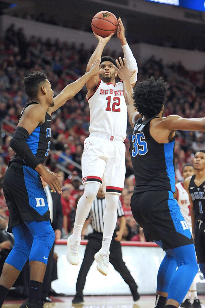 Allerik Freeman, a graduate student guard, towers over both Marcus Bagley iii and Javin DeLaurier, to shoot the ball. The North Carolina State University mens basketball team caught a win against 4th ranked Duke saturday night 96-85.