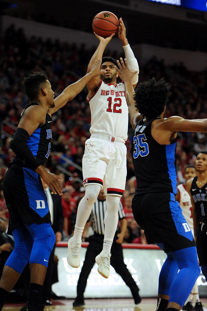 Allerik Freeman, a graduate student guard, towers over both Marcus Bagley iii and Javin DeLaurier, to shoot the ball. The North Carolina State University mens basketball team caught a win against 4th ranked Duke Saturday night 96-85.