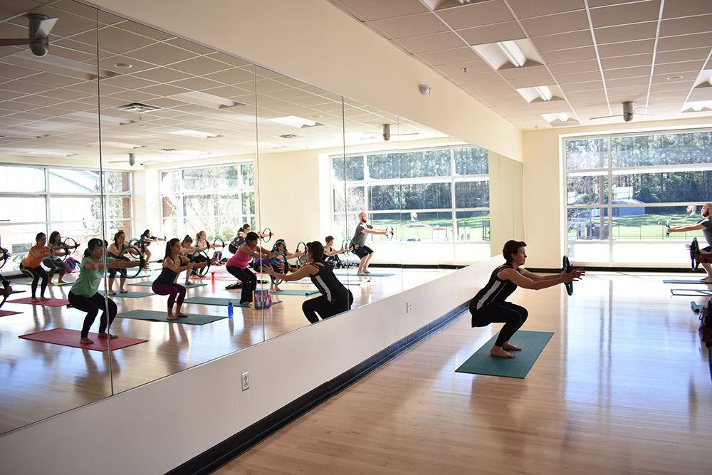 Lynn, a fitness group instructor, begins her yogalates class with a warmup exercise that engages the core and focuses on breathing. Yogalates is a hybrid course of yoga and Pilates. Yogalates utilizes the core coordination of Pilates, with the added flexibility of yoga to develop a well-rounded workout. Lynn says that "this time of the year the classes are usually full since people want to stick to their New Year's resolution." The class is one hour long and is offered Wednesday afternoons at 12:10 p.m. at the Carmichael Recreation Center.