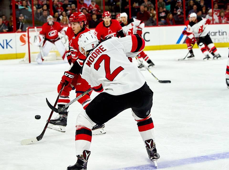 New Jersey Defensman John Moore battles Carolina Hurricanes forward Teuvo Teravainen to put a shot on Canes goalie Cam Ward Cam Ward Sunday, February 18 at PNC Arena during a 3-2 New Jersey overtime win. Moore had an assist in the game.