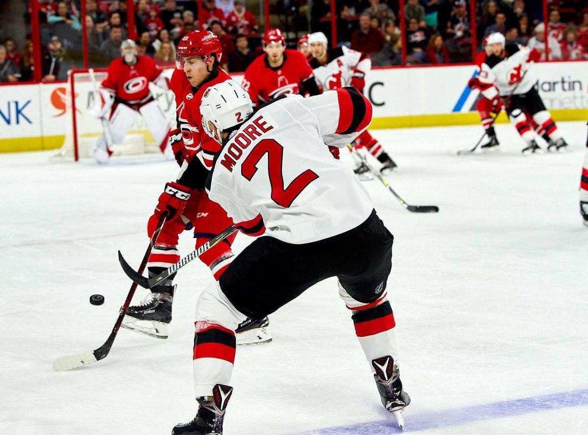 New Jersey Defensman John Moore battles Canes forward Teuvo Teravainen to put a shot on Cam Ward Sunday, February 18 at PNC Arena for a 3-2 overtime New Jersey win. Moore had an assist 15:33 in the second period.