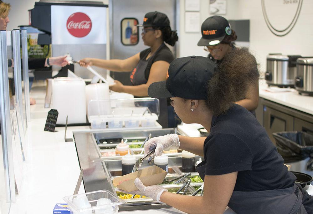 Staff members of the new Pok&#233; Bar on Hillsborough Street create pok&#233; bowls for customers Wednesday. The business aims "to provide fresh, healthy food in a fast and efficient way without sacrificing quality," offering a make-your-own approach to a deconstructed sushi bowl.