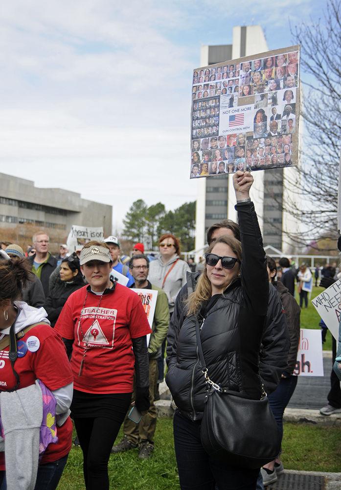 N.C. State University alumnus Claire Healey raises her sign high at the "March for Our Lives" in Halifax Mall on Saturday, Mar. 24. 2018. Healey stated that she attended the march because she believed that as a country "we are so far past the point of where we need to be with gun reform" and that she "came to support the cause" . Healey's sign displayed many of the faces that were killed in major school shootings in the United States.