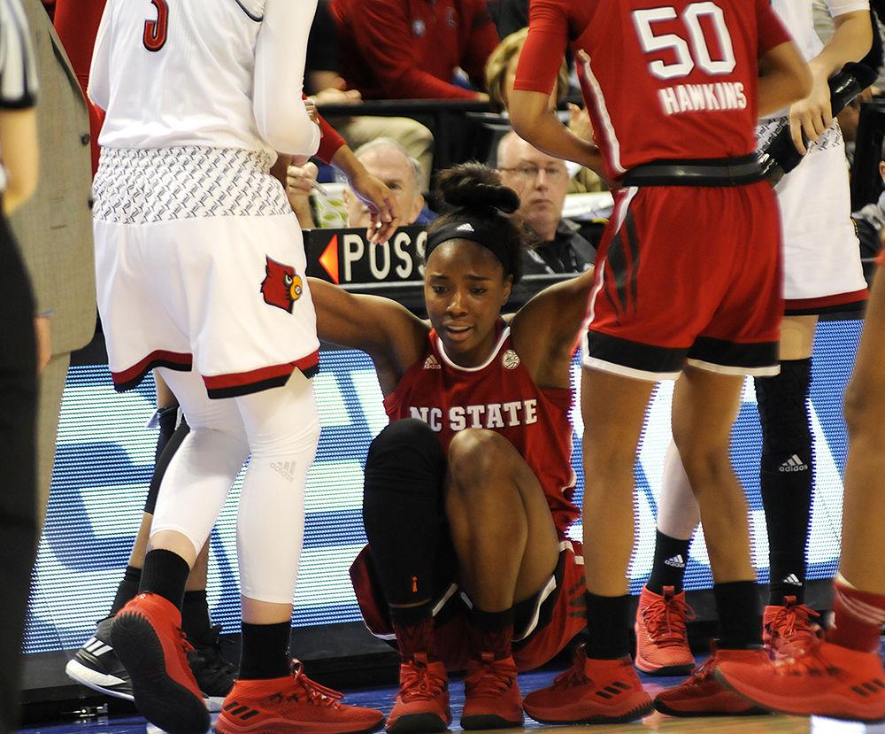 Fellow teammate Armani Hawkins and Louisville player Sam Fuehring help senior forward Chelsea Nelson to her feet at the ACC women's basketball semifinal against Louisville in Greensboro Coliseum on Saturday. The Wolfpack lost to the Cardinals with a final score of 64-59.