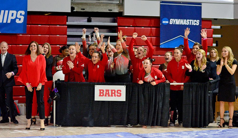 The NC State gymnastics team cheers for a teammate who finished performing on the uneven bars in the NCAA Regional Championship. The meet took place in Reynolds Coliseum on Saturday and the team came in 3rd place overall.