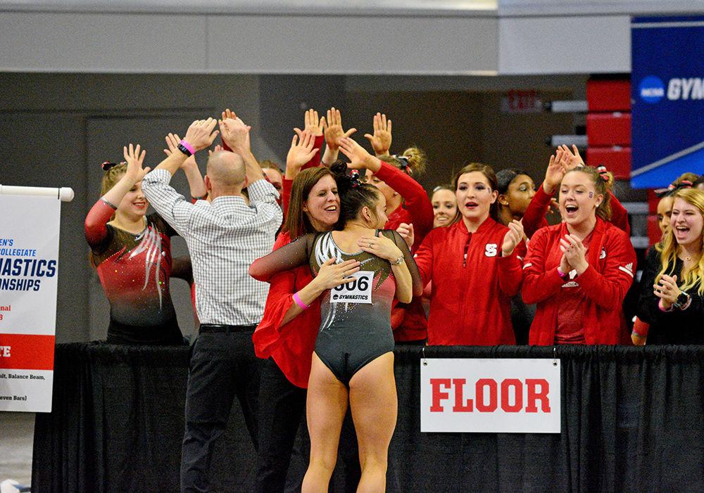 Senior Mackenzie Itcush hugs coach Kim Landrus and her team cheers after she performs her floor routine. She scored 9.850 on floor at the NCAA Regional Championship in Reynolds Coliseum on Saturday.