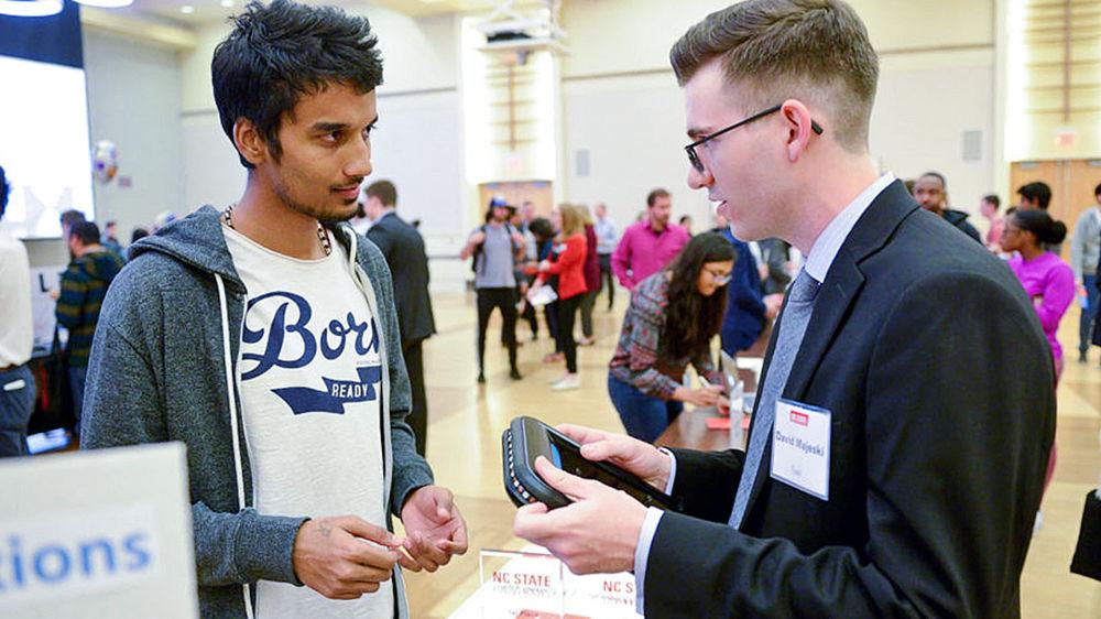 Graduate student David Majeski, right, of Tueri, explains the device to an interested prospect at the eGames Expo.