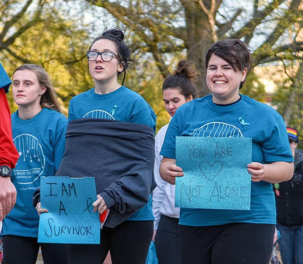 Rachel Neville, a third-year studying mathematics education, and Ari Alexandrescu march with signs during Take Back the Night on Wednesday in Stafford Commons. Take Back the Night is an annual event that looks to reclaim the night and NC State's campus for survivors of sexual assault.