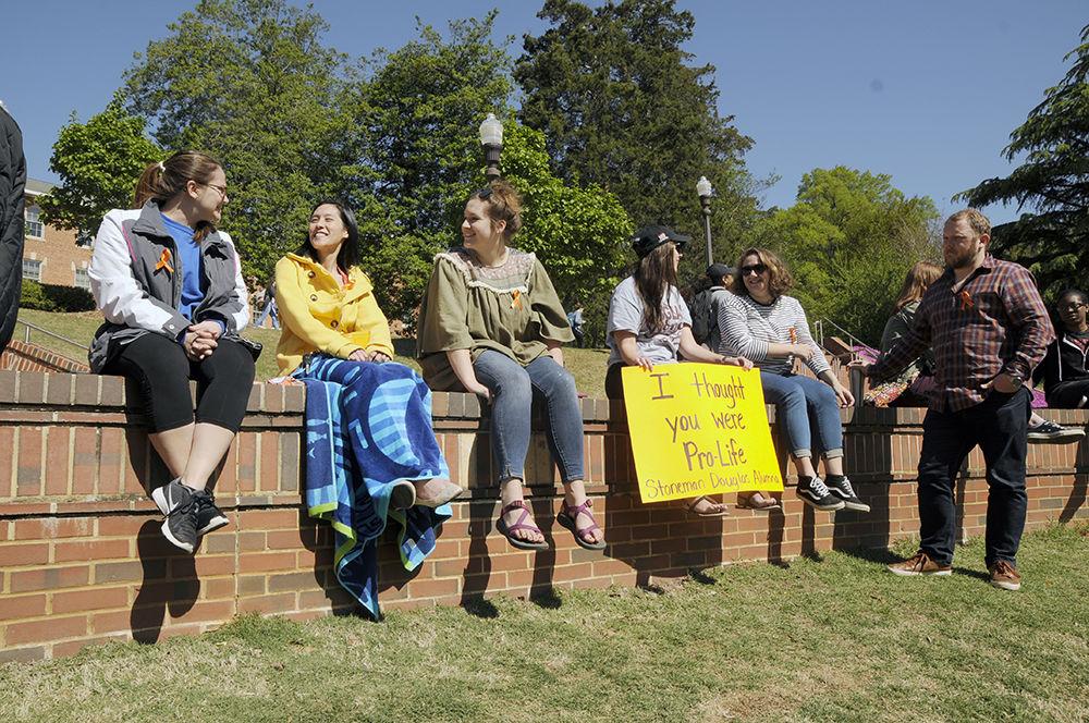From the left, Jennifer Lutz, Josephine McKelby, Alex Bailey, Marie Gualtieri and Leslie Pierce, all PhD students studying sociology, sit on a brick wall in the Court of North Carolina at the NC State Walkout on Friday. The Walkout was hosted in solidarity with the victims of gun violence in the United States and calls for campaign finance reform to stop lobbying from the NRA.