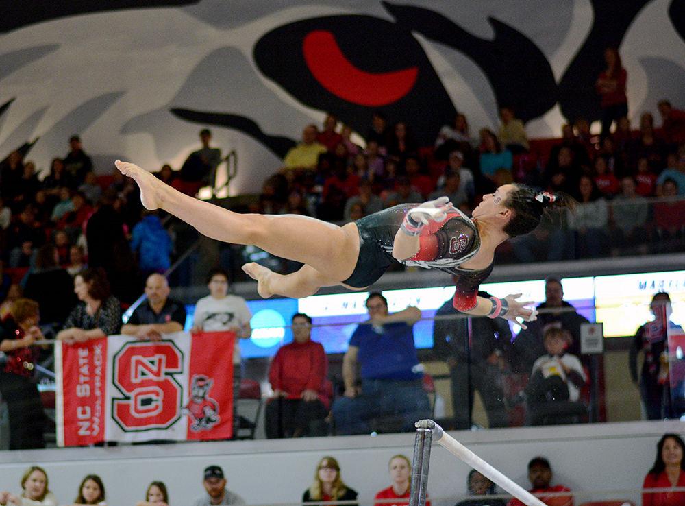 Junior Caitlyn Fillard in midair as she moves from one bar to the other. She scored 9.775 points in the uneven bars at the NCAA Regional Championship in Reynolds Coliseum on Saturday.
