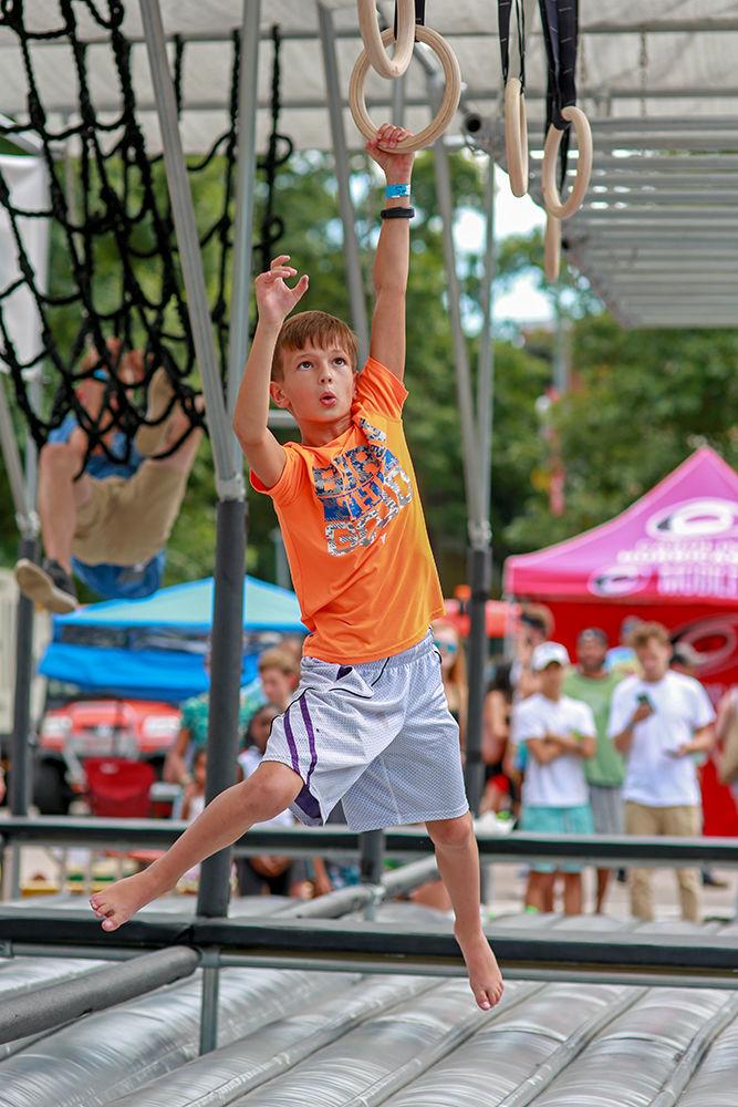 Lucas Faby, 10, swings from ring to ring on the mobile ninja warrior setup at Packapalooza on Saturday, August 25.