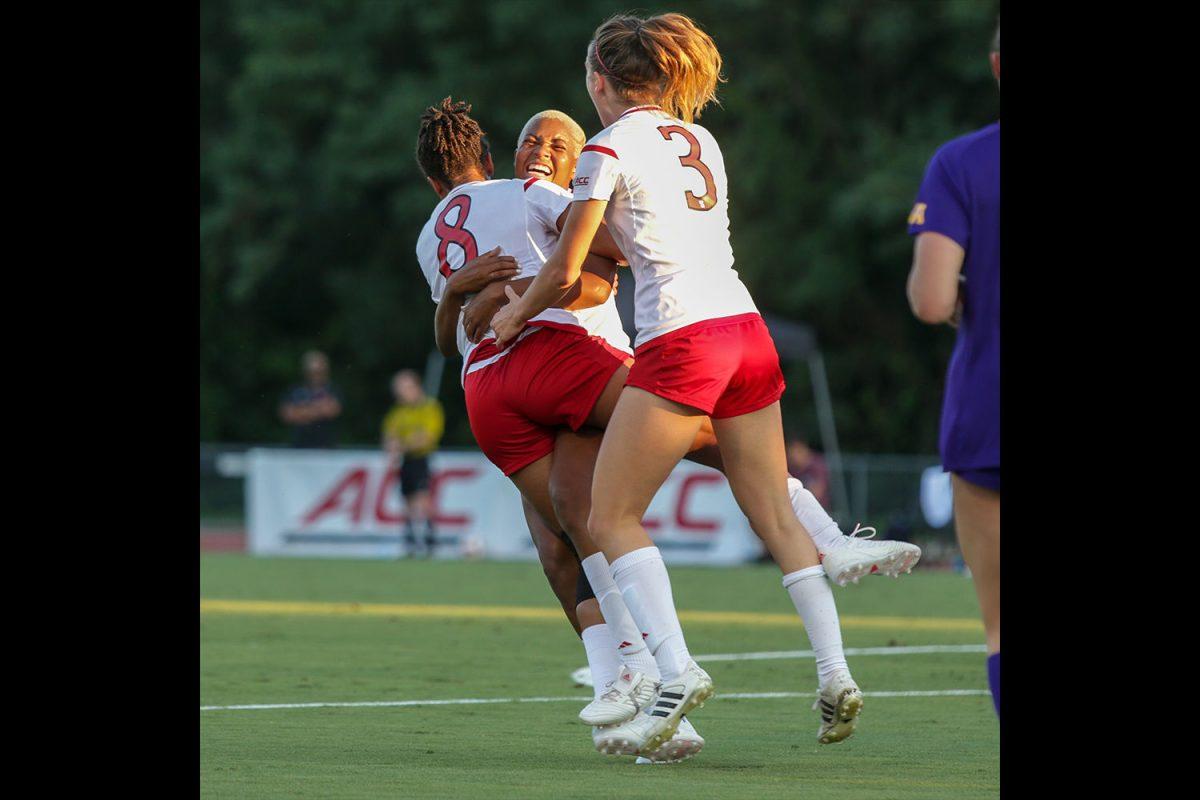 Junior midfielder Tziarra King and junior defender Krissi Schuster hug junior forward Kia Rankin after her goal in the fifteenth minute. The Pack put on the pressure with 29 shots to East Carolina's 12, but were not able to break the 1-1 tie on Thursday, August 23 in Dail Soccer Stadium.