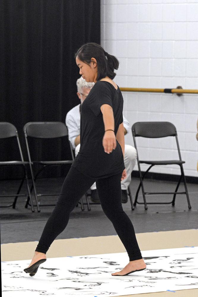 Lillian Tseng, a third-year studying chemical engineering and a member of NCSU Dance Company, tiptoes across a sheet of paper after stepping in ink during a Master Class hosted by the NCSU Dance Program in Carmichael Gymnasium on Wednesday, Sept. 19. This Master Class was entitled "John Cage's STEPS: A Composition For A Painting with Ray Kass".
