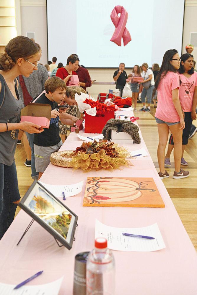 Festival attendees browse through the items on auction at the 2018 Chocolate Festival in Talley Ballroom, on Friday, Sept. 28. The Chocolate Festival is an annual event hosted by the NC State Women's Center to benefit the Kay Yow Cancer Fund.