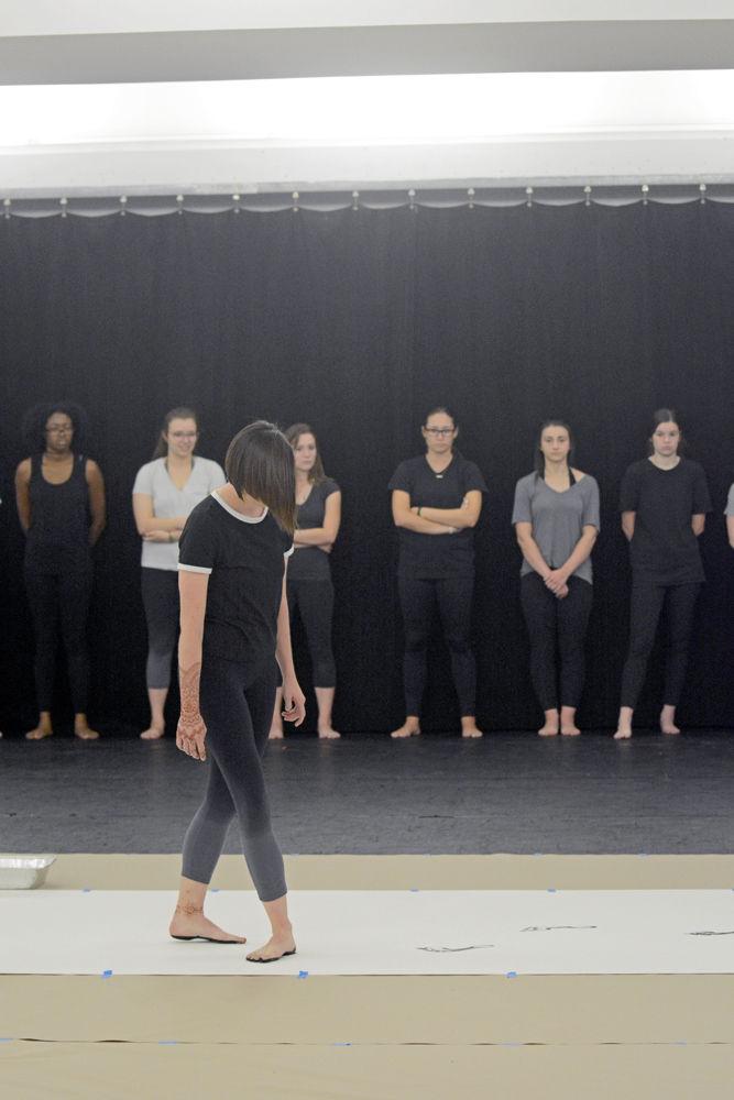 Casey Graff, a second-year studying animal science and a member of NCSU Dance Company, begins a composition of "John Cage's STEPS" by leaving her footprints on a long piece of paper after stepping in black paint. This composition was the feature of a Master Class hosted by the NC State Dance Program in Carmichael Gymnasium on Wednesday, Sept. 19.