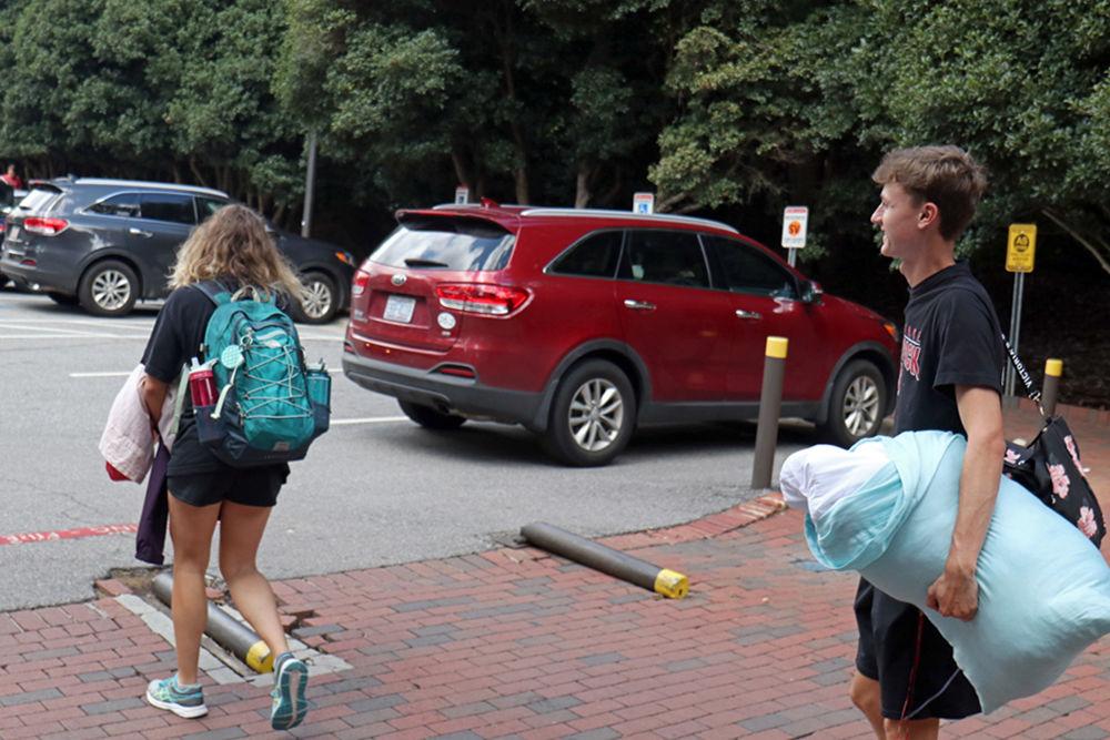 Agusta Schmitz, a first-year studying fashion textiles, and Hayden Edmondson, a first-year studying biology, carry their belongings out to their vehicles on Wednesday, Sept. 12 at the Student Services Lot.