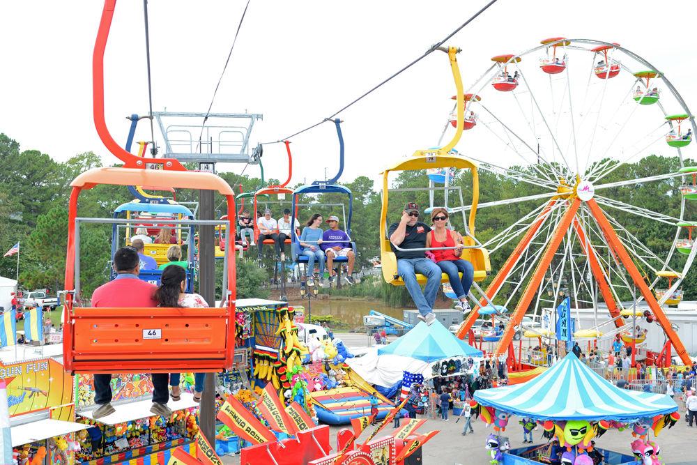 Fairgoers ride on the North Carolina State Fair Flyer next to a Ferris wheel at the North Carolina State Fairgrounds on Oct. 13, 2017. The State Fair Flyer was introduced at the 2016 State Fair and allows fairgoers the opportunity to view the fair from above. 2017 marked the 150th annual State Fair.